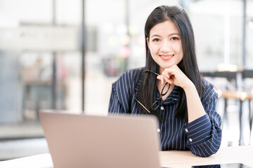 Young beautiful joyful woman smiling while working with laptop