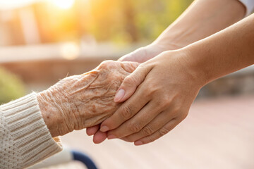 Elderly Hand Held By A Younger Hand In Sunlight Expressing Care And Love The