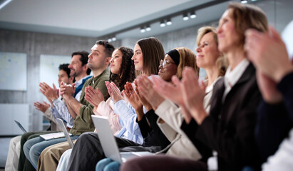Smartly dressed audience of diverse business professionals applauding