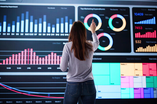 Woman analyzing stock data on big screen - Powered by Adobe
