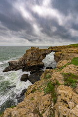 The rocky arch at the rocky coast at the sea