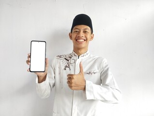 Moslem Asian man smiling happy and give thumb up while holding blank handphone screen
