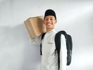 Muslim man carrying cardboard box and black bag with happy face