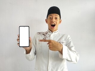 Asian Muslim man points to blank smartphone screen with shocked expression 