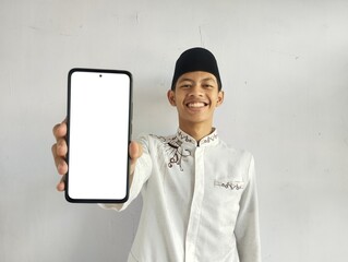 Moslem Asian man smiling and showing blank mobile phone screen