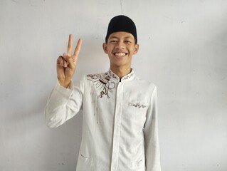 Moslem Asian man smiling at the camera and showing two fingers