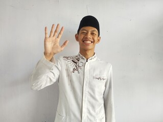 Moslem Asian man smiling at the camera while showing five fingers sign