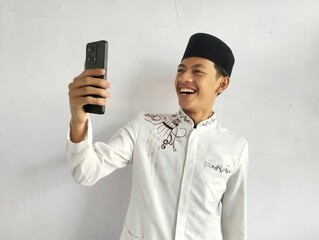 Moslem Asian man waving hand with happy face when doing video call with his family