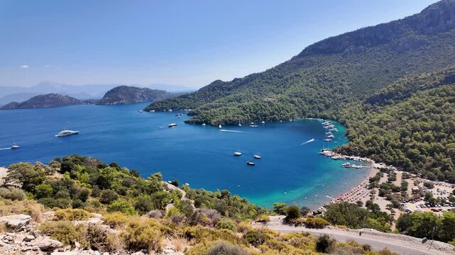 Sarsala Beach Bay in Dalaman, Turkey, a serene Mediterranean cove with crystal-clear waters, lush green hills, and anchored yachts, offering a perfect summer escape.