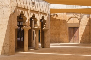 Street landscape of the of old historical Dubai city with typical sandstone facades and arches, light and shadow. Middle eastern architecture.