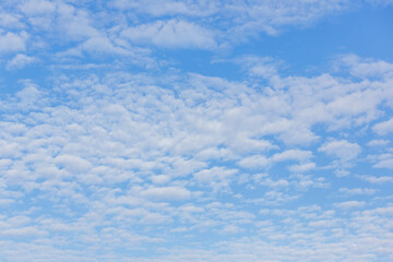 A vast blue sky with scattered white clouds, creating a peaceful and serene atmosphere, perfect for backgrounds and nature themes.