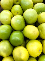 Fresh limes and lemons stacked together at a local market during the afternoon
