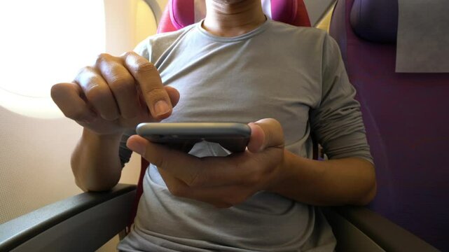A man is using his cell phone while sitting in a chair. Concept of relaxation and leisure, as the man is focused on his phone rather than his surroundings