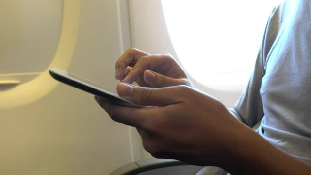 A man is using his cell phone while sitting in a chair. Concept of relaxation and leisure, as the man is focused on his phone rather than his surroundings