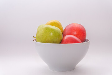 A bowl with pears and apples on a white background, side view
