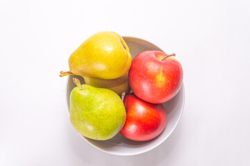 A bowl with pears and apples on a white background, top view