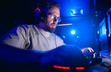 Caucasian male adult gamer focused on computer gaming in dimly lit room © Parilov