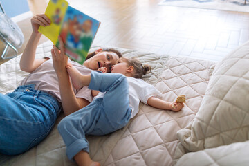 Little girl listens to her mom reading a book