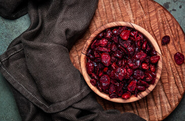 Organic sun dried cranberries in wooden bowl on green background, top view