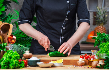 Chef cutting broccoli with Japanese knife. Cozy kitchen with wooden table, kitchenware, vegetables, herbs and ingredients for cooking. Home food, cooking, recipes, food blogging