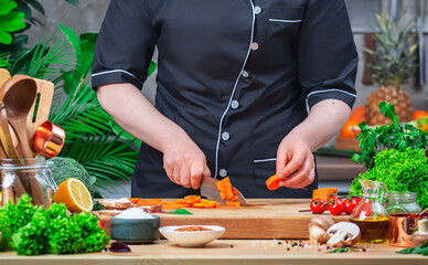 Chef cutting broccoli with Japanese knife. Cozy kitchen with wooden table, kitchenware, vegetables, herbs and ingredients for cooking. Home food, cooking, recipes, food blogging