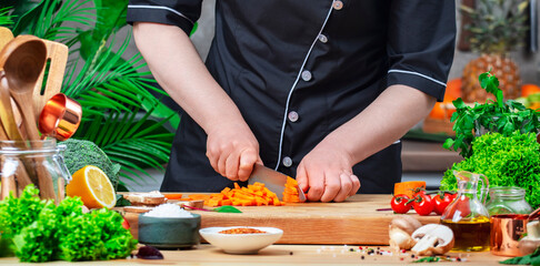Chef cutting broccoli with Japanese knife. Cozy kitchen with wooden table, kitchenware, vegetables, herbs and ingredients for cooking. Home food, cooking, recipes, food blogging