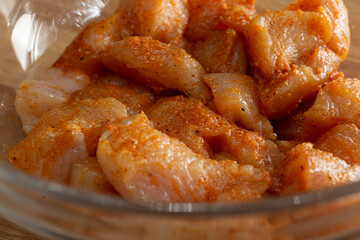 A closeup view of raw marinated chicken in a glass bowl.