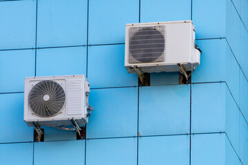 Air conditioning compressors on blue wall of building