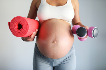 Pregnant woman ready for fitness workout. Fitness equipment.