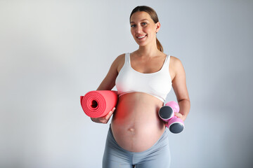 Beautiful pregnant woman ready for fitness workout. Fitness equipment.