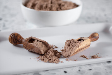 A view of wooden scoops of chocolate protein powder.