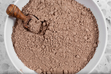 A top down view of a bowl of chocolate protein powder.