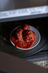 A view of a plate of rice meatballs in the microwave.
