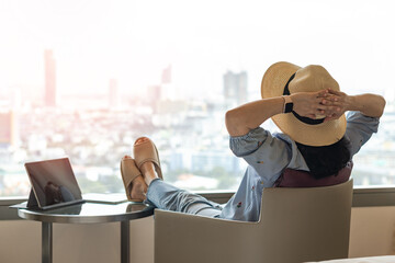 Work-Life balance, life quality, work and travel concept with business woman relaxing sitting in rest, take it easy in modern hotel guest room or luxury home living room with notebook and city view