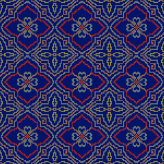 Seamless fabric pattern with four petal pixel flowers in a red frame alternating with yellow flowers in a brown diamond frame on a dark blue background.