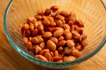 A view of a glass bowl of canned pinto beans.