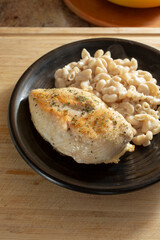 A view of a plate of chicken breast and macaroni and cheese.