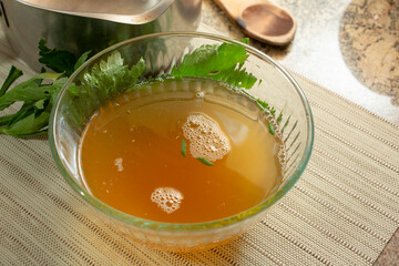 A view of a glass bowl filled with bone stock.