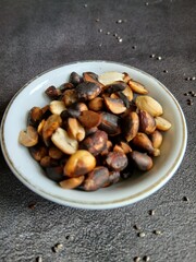 Bowl of burnt Roasted Nuts on Gray Background