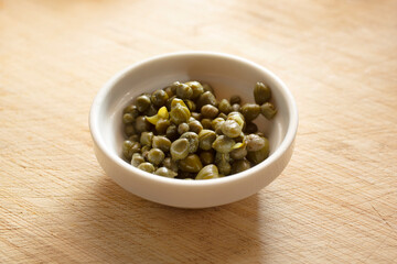 A closeup view of a condiment cup of capers.