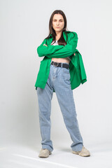 Fototapeta premium Cute young girl in green shirt and blue jeans posing on a white background