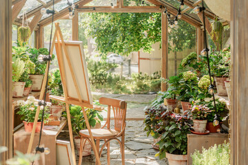 Creative greenhouse studio: an easel surrounded by lush greenery