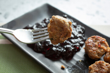 A view of a grape jelly meatball on a fork.