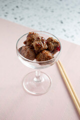A view of a coupe glass filled with small grape jelly meatballs.