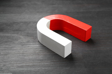 One horseshoe magnet on black wooden table, closeup