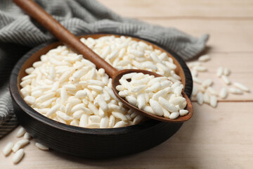 Puffed rice in bowl and spoon on white wooden table, closeup