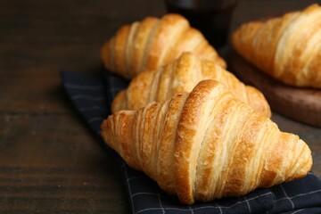 Tasty fresh croissants on wooden table, closeup. Puff pastry