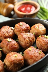 Tasty meatballs with green onion in baking dish on table, closeup