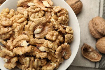 Peeled walnuts in bowl on table, top view