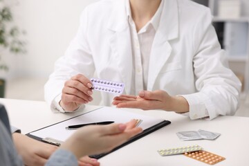 Gynecologist recommending contraceptive pills to woman in clinic, closeup